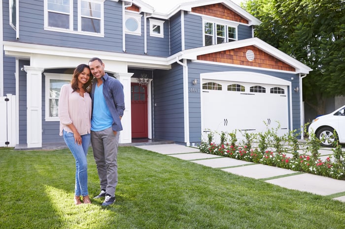 Smiling man and woman standing in front of house