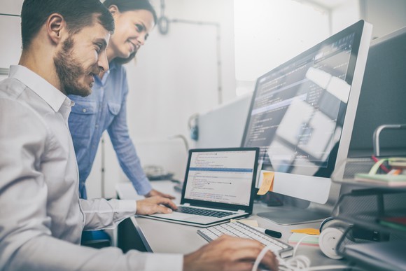 Male and female co-workers look at computer screens.