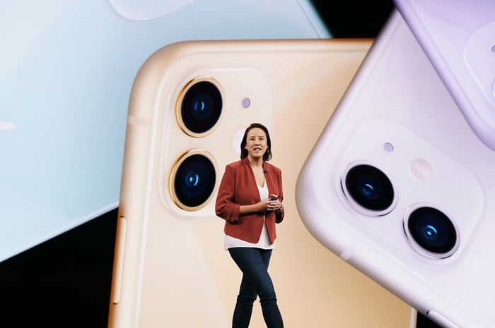 A woman standing in front of a display featuring images of the iPhone 11.