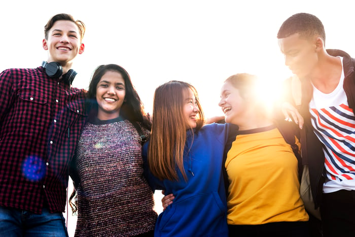 Group of school friends outdoors arms around one another.