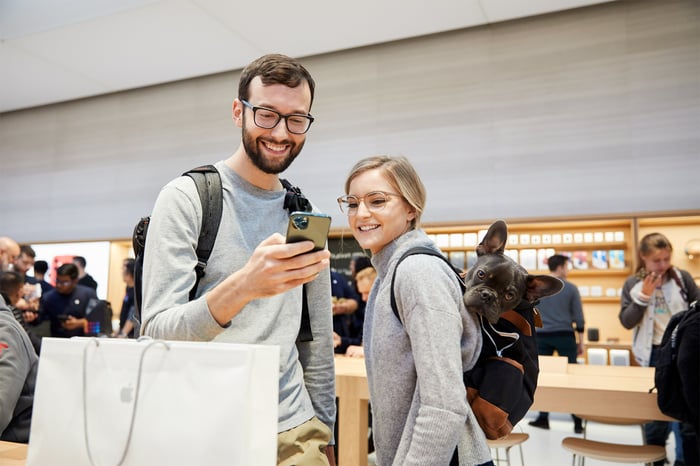 A man and a woman in an Apple Store looking at an iPhone 11 Pro