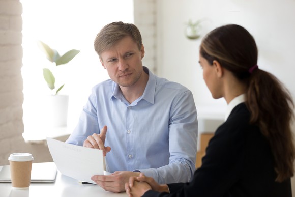 Man holding document while looking at woman suspiciously