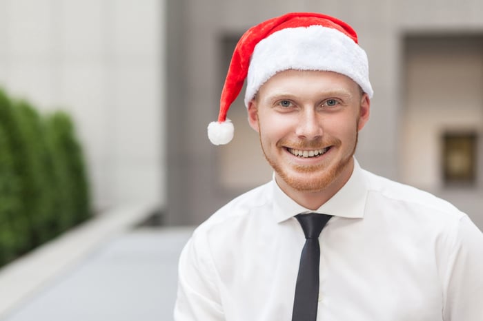 Smiling man in collared shirt and tie wearing Santa hat