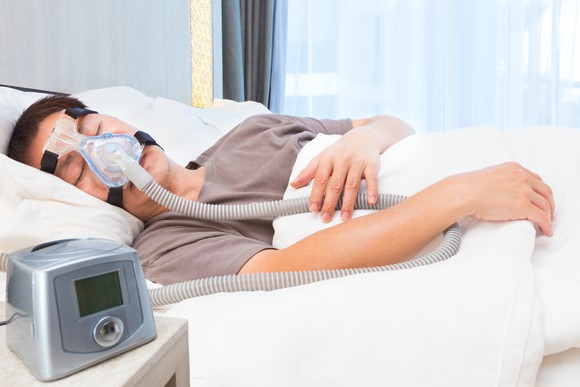 Man sleeping with CPAP machine on face.