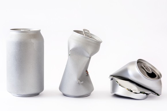 A regular beer can, a slightly crushed beer can, and a fully crushed beer can