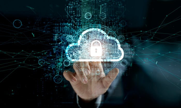 A man touches the image of a cloud with a padlock icon in its center on a screen to illustrate network security.