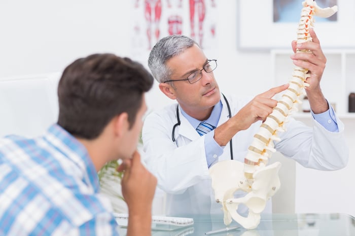 Physician showing a patient a human spine model