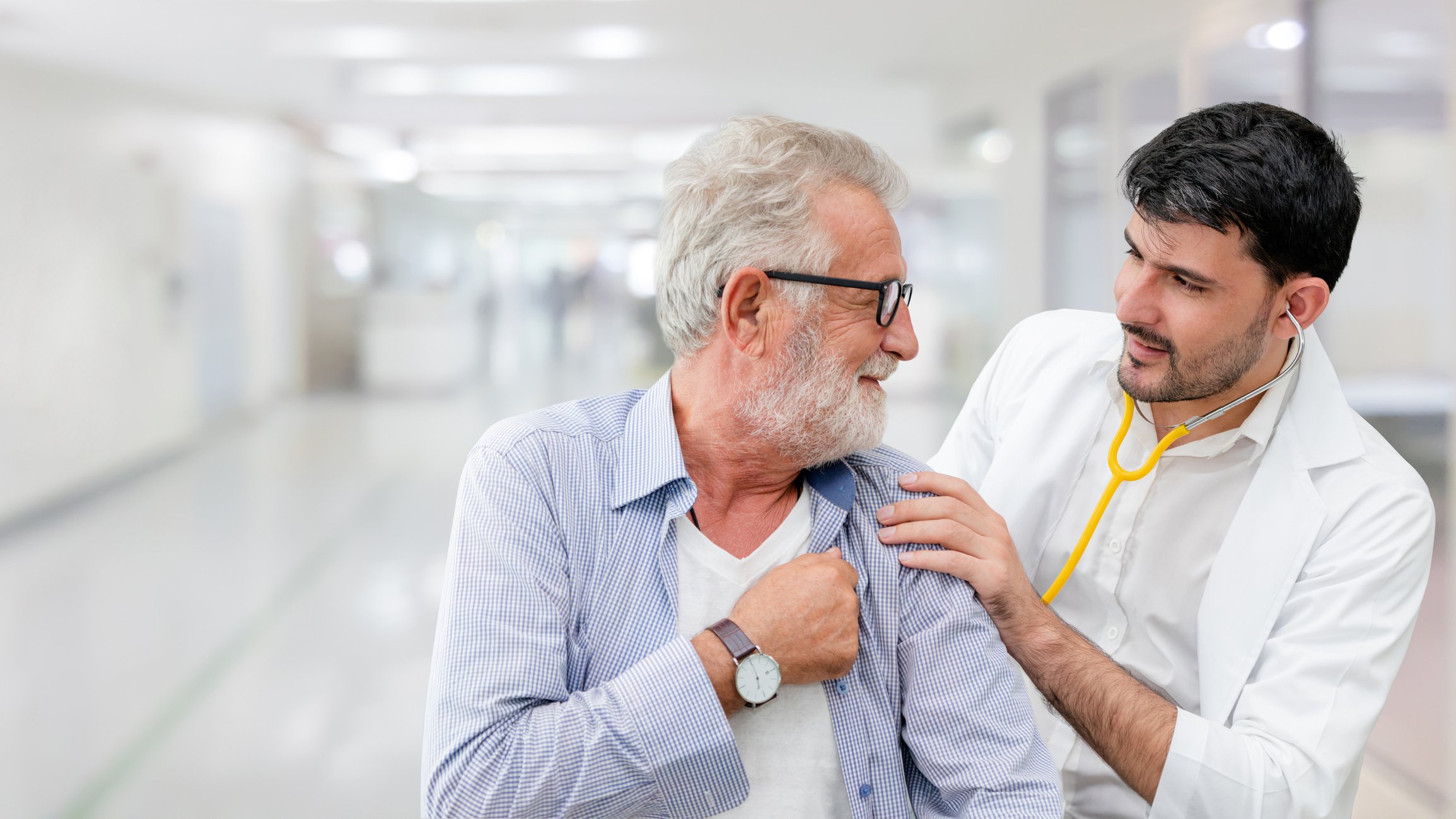 Healthcare provider listening to breath sounds of mature older male patient