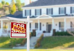 for sale sign with word sold pasted on it in front of house home real estate