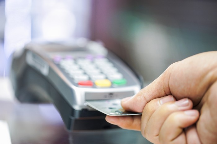 A person inserting a credit card into a reader in a retail store. 