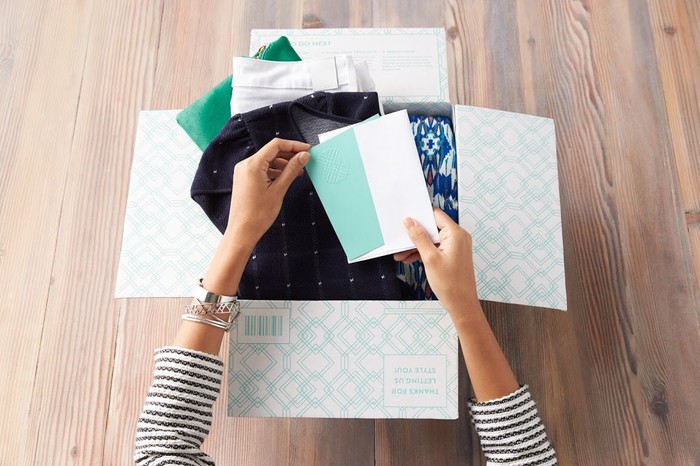 A woman opening up a personalized box of clothing. 