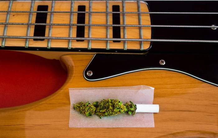 An unrolled marijuana cigarette on top of a bass guitar.