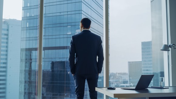 A businessman staring out of an office window.