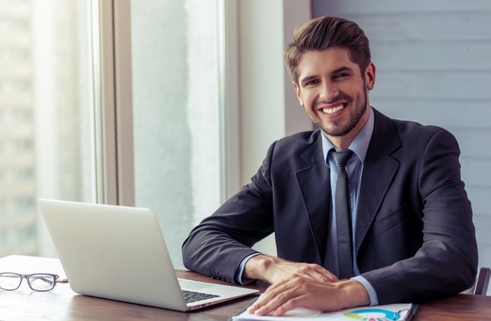 Smiling man in business suit and tie at laptop