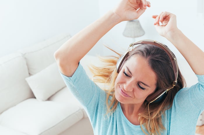 A girl wearing headphones while smiling and dancing