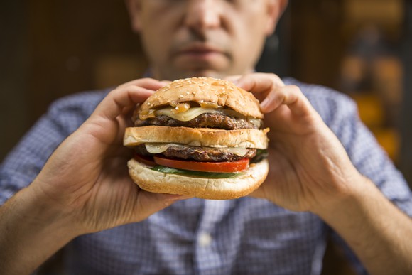 Man holding up a large double-meat burger.