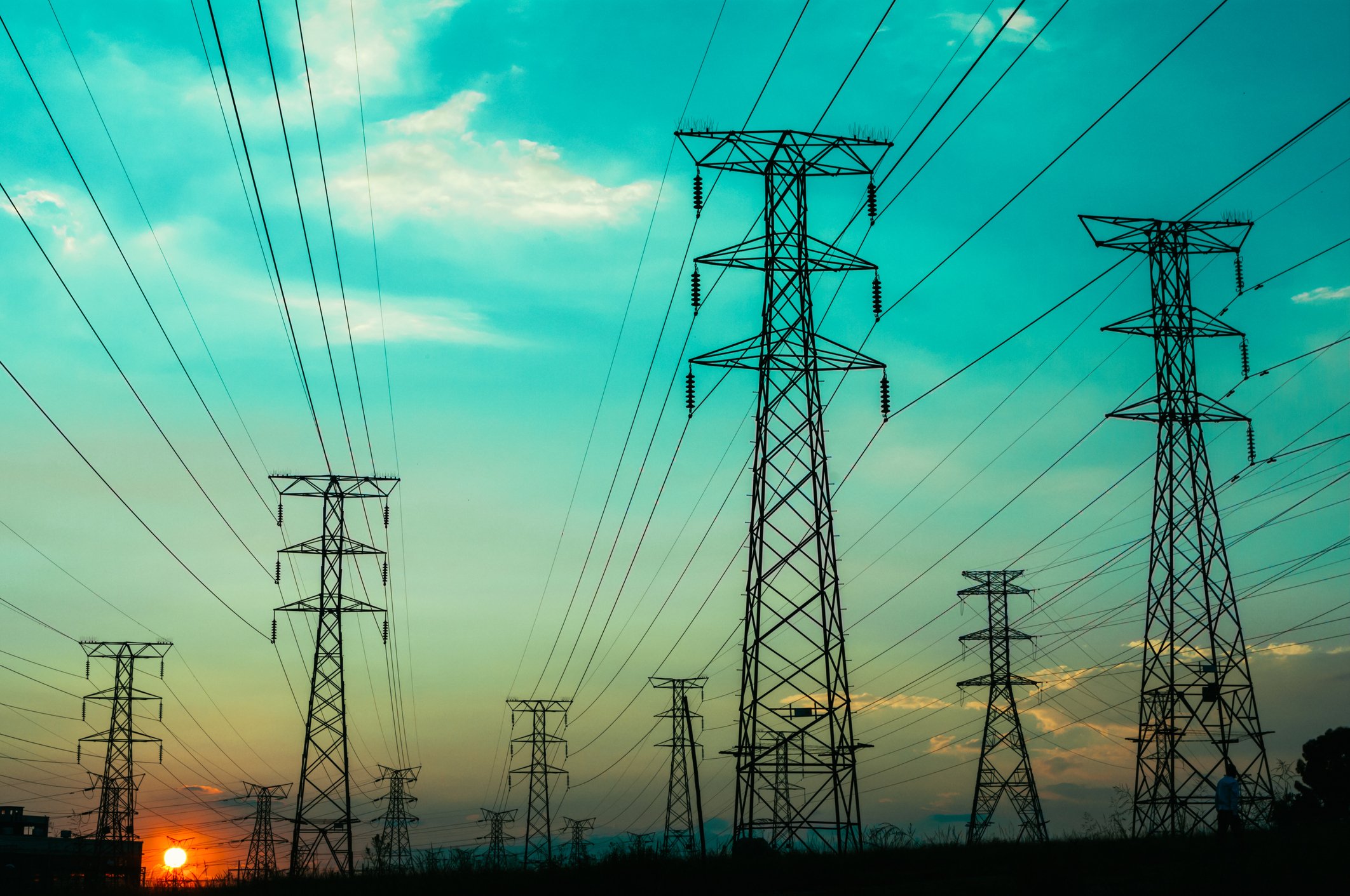 electric writes and wire towers with a sunset in the background