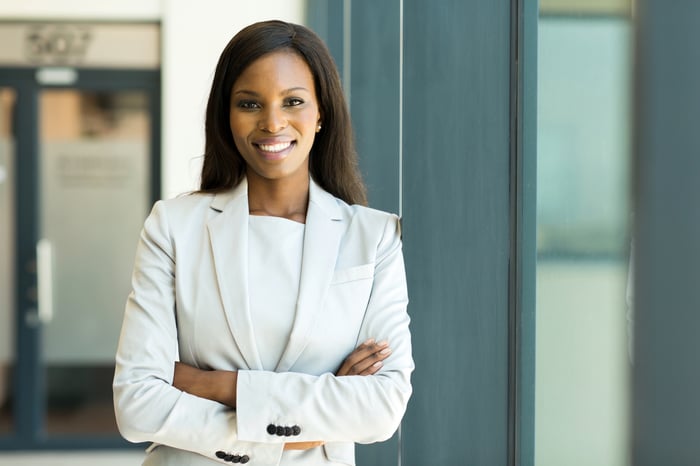 Smiling woman in white business suit with arms crossed