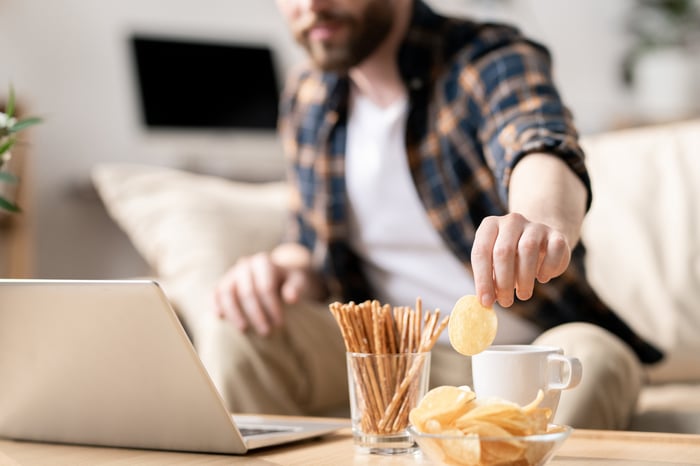 A man eats snacks while working at his computer.