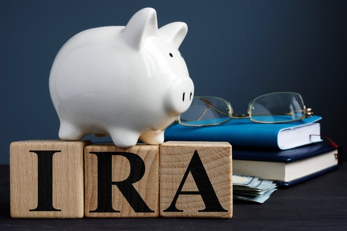 Piggy bank standing on IRA letters with glasses and books in background