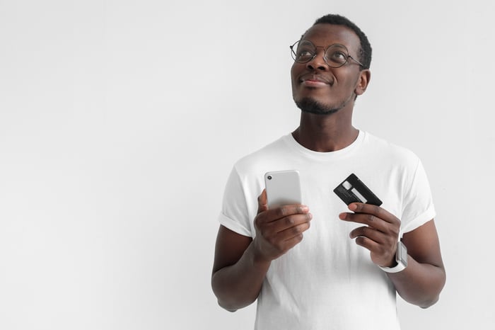 A man holding his smart phone in one hand and a credit card in the other hand