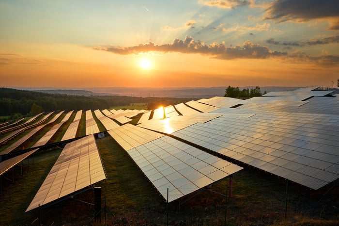 Solar panels with the sun setting in the background.