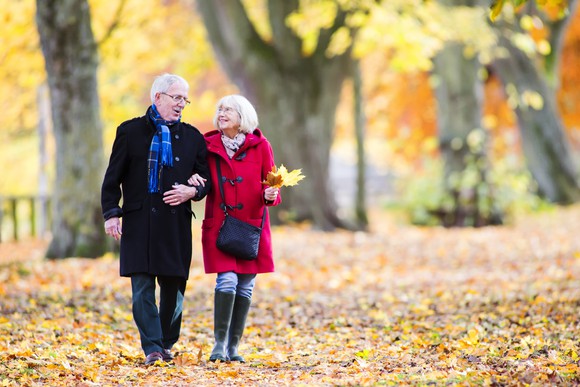 Senior couple walking on leaves in the fall
