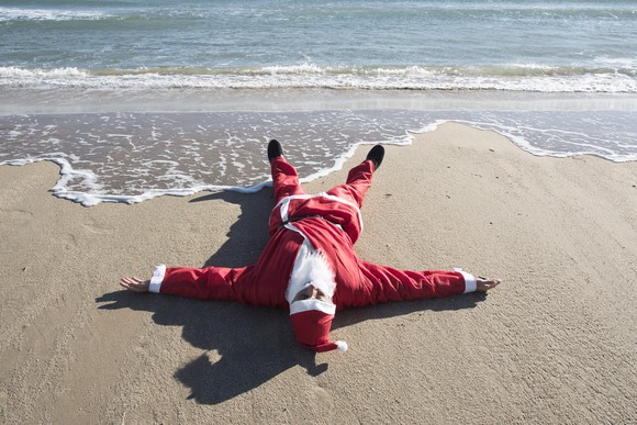 Santa Claus lying on a beach.
