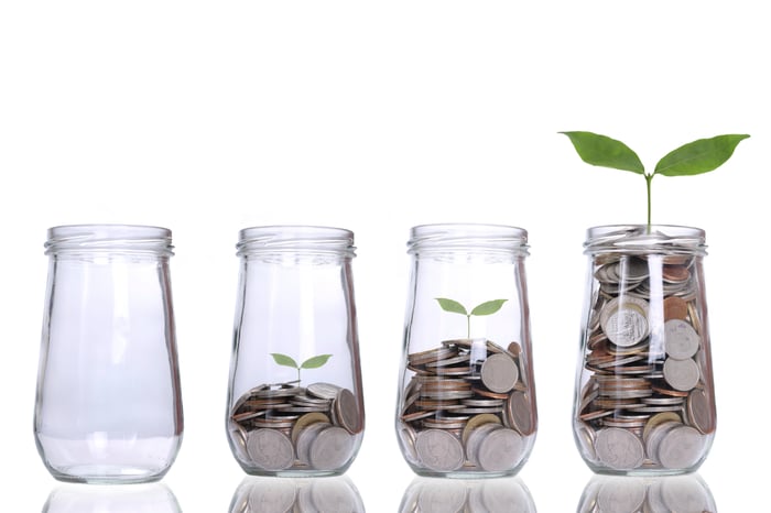 Jars with increasingly large piles of coins that have plants growing out of them