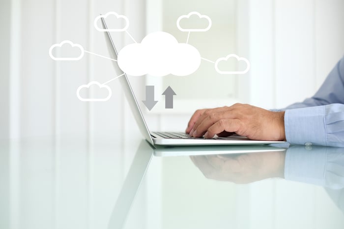 A man typing on a laptop with white clouds floating above the keyboard.