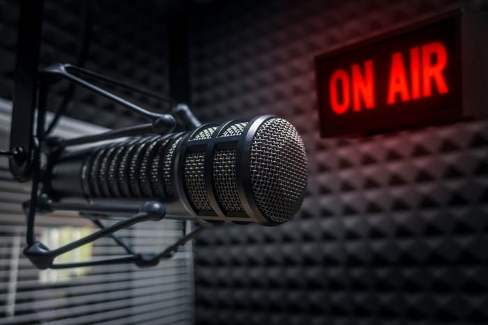 An audio microphone up close with a red on air sign in the background of a music studio