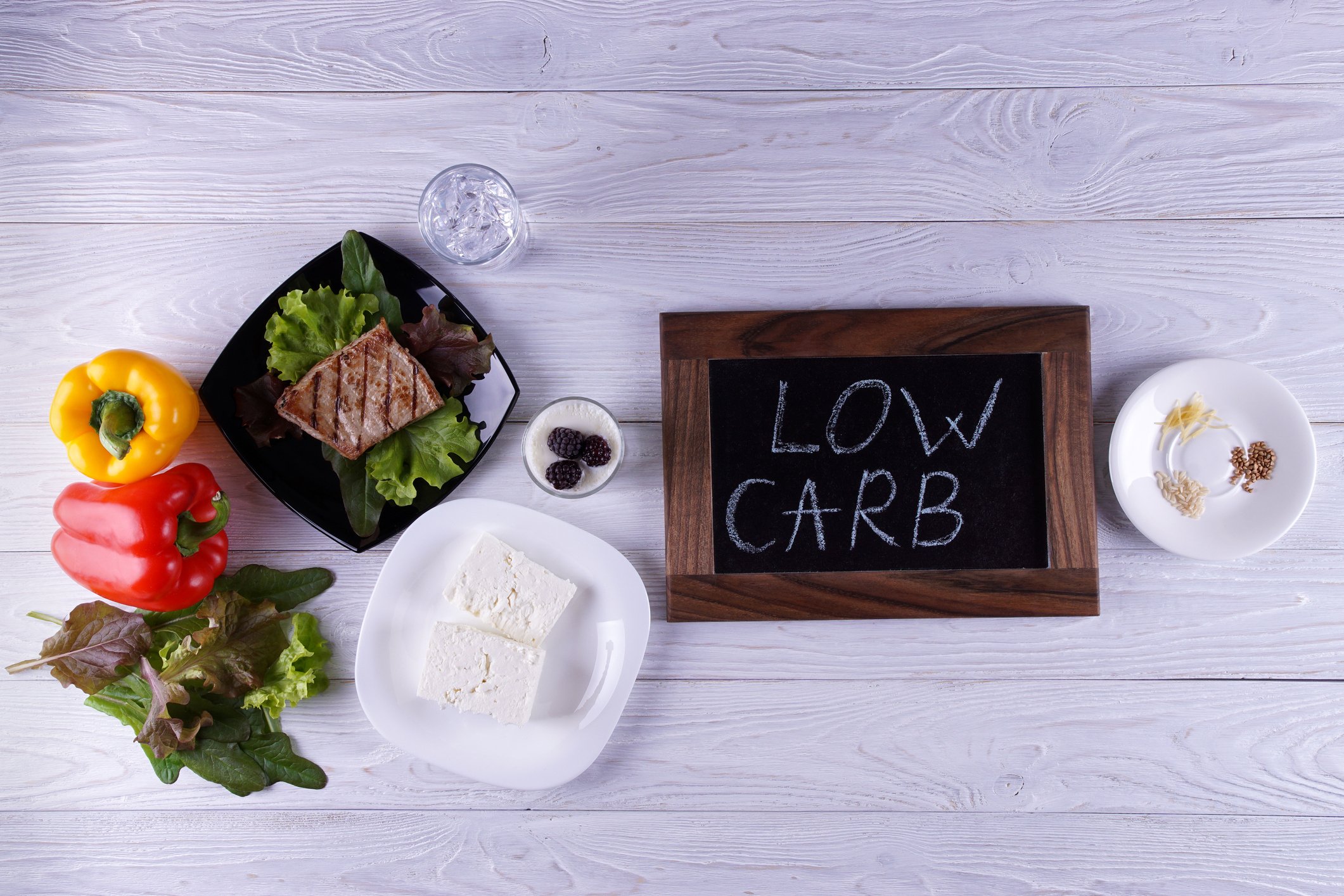 Low carb written on a small blackboard surrounded by various low carbohydrate foods