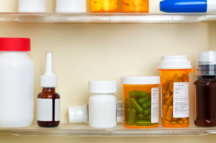 A medicine cabinet shelf with various bottles of prescription medications sitting on it.