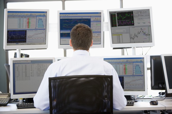 A man looks like at five computer screens showing stock movement