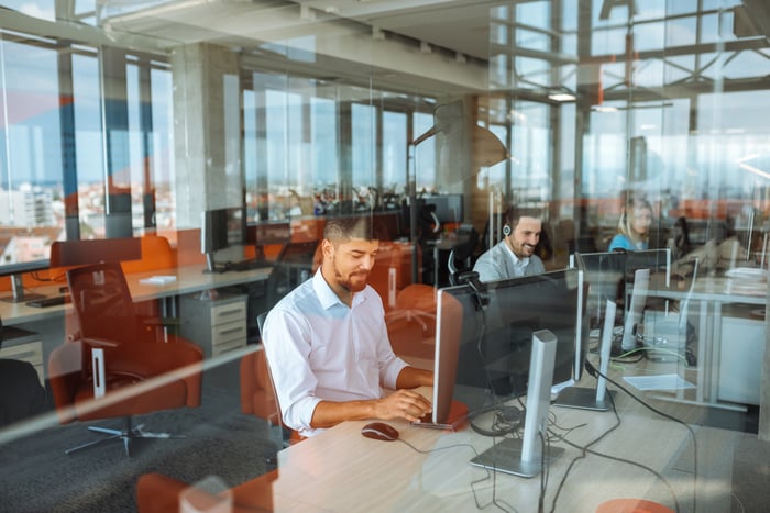 People working on computers at a row of desk's in an office.