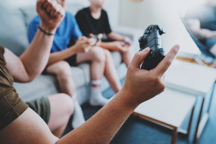 A group of boys sitting on a couch and chairs holding video game controllers