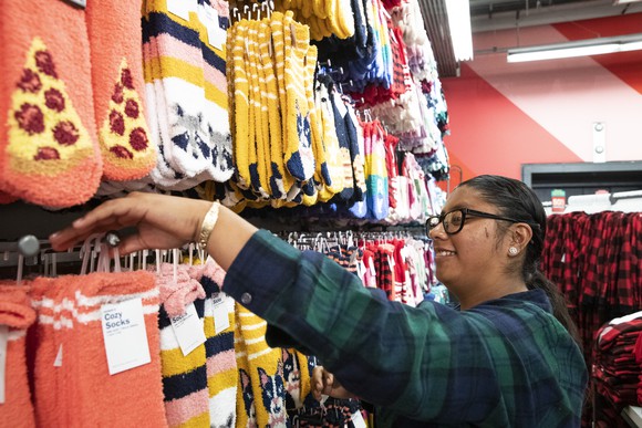 An Old Navy Employee puts socks on the shelves.