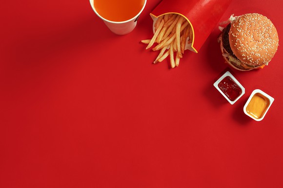 A hamburger, fries, and drink sitting on a red surface.