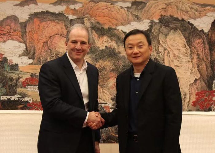 Jim Magats and Larry Wang smiling and shaking hands