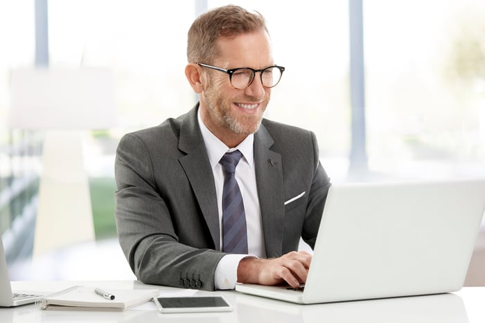 Smiling man in suit typing on laptop