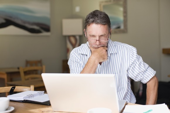 Older man squinting at laptop screen