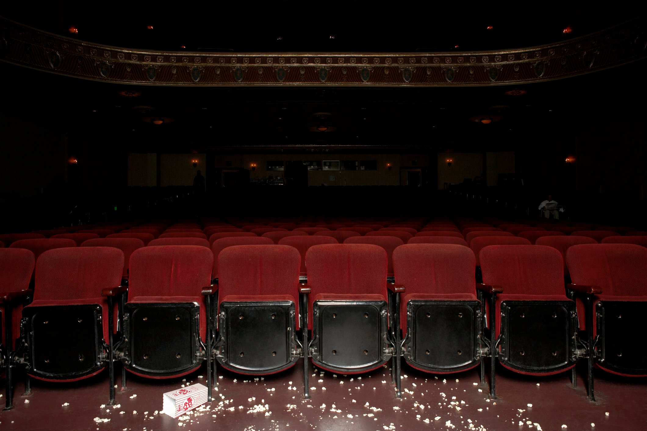 Darkened empty movie theater with floor littered with popcorn