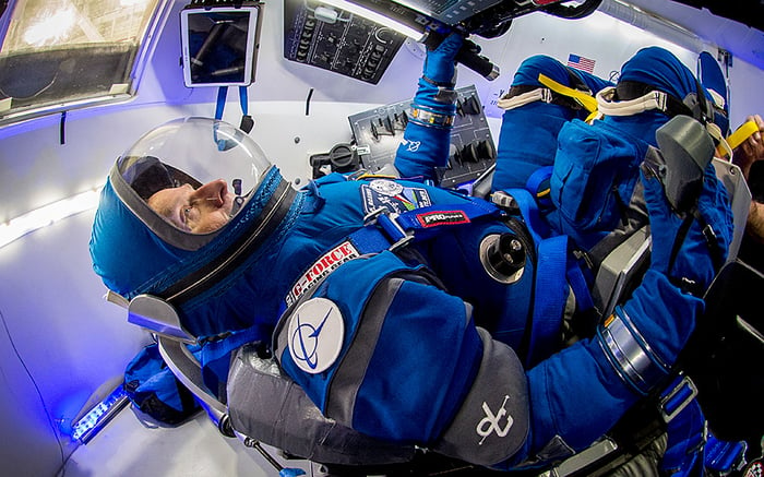 Astronaut in spacesuit within a Starliner space capsule