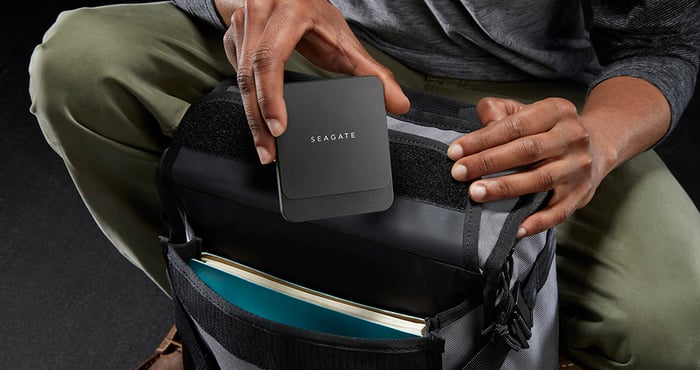 Traveler putting a Seagate hard drive into a backpack
