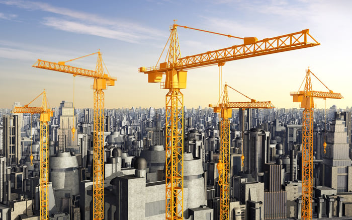 Construction cranes in front of skyscrapers.