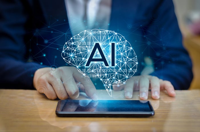 Man using a cell phone that's sitting on a flat surface and has an image of a connected brain with AI on it hovering above.