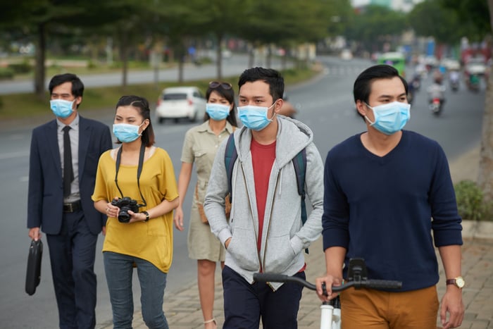People on the sidewalk wearing face masks