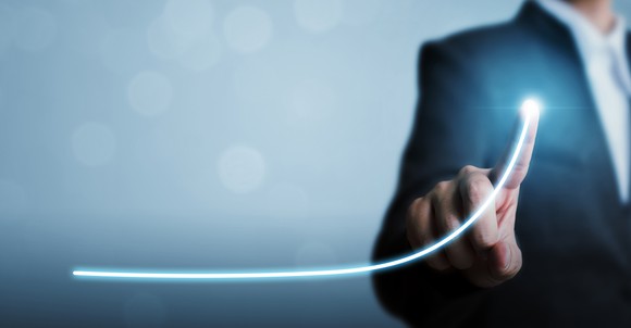 A businessman pointing at a line that's rising upwards.