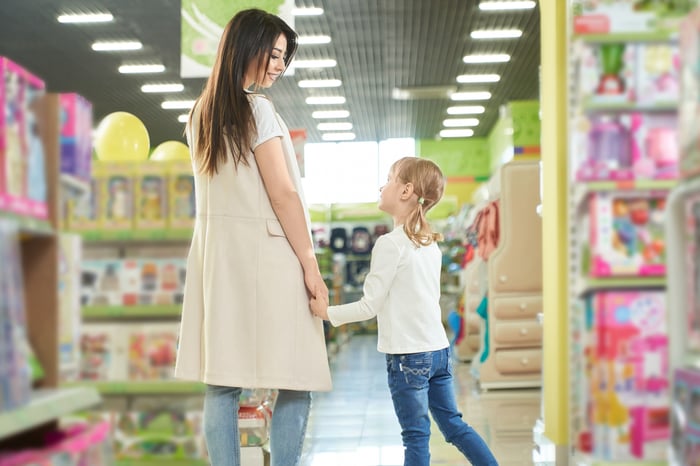 A mother and daughter holding hands inside a toy store