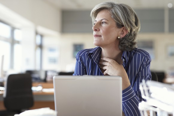 Mature woman on laptop looking off into the distance